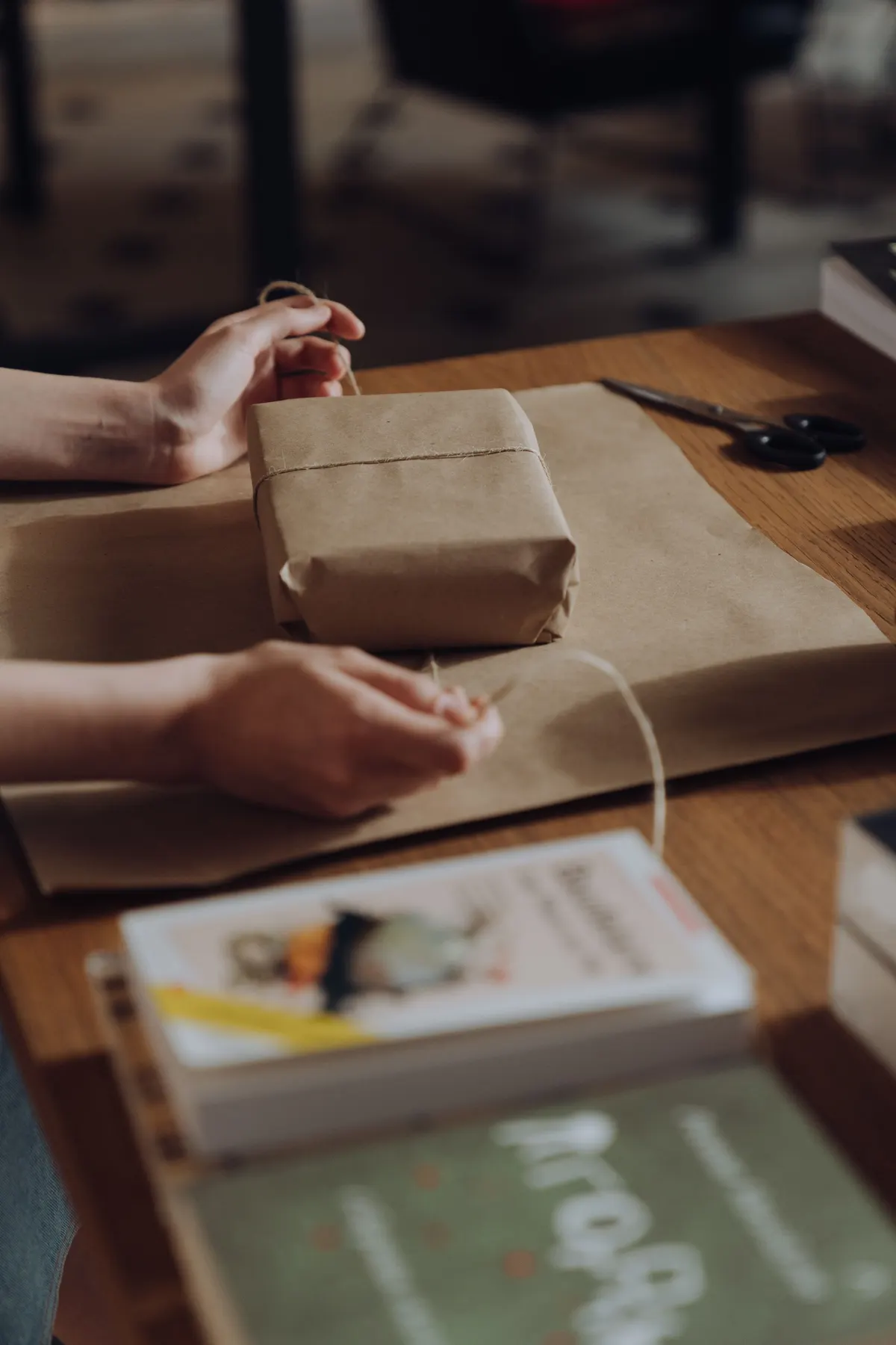 Hands carefully wrapping a parcel with paper and twine